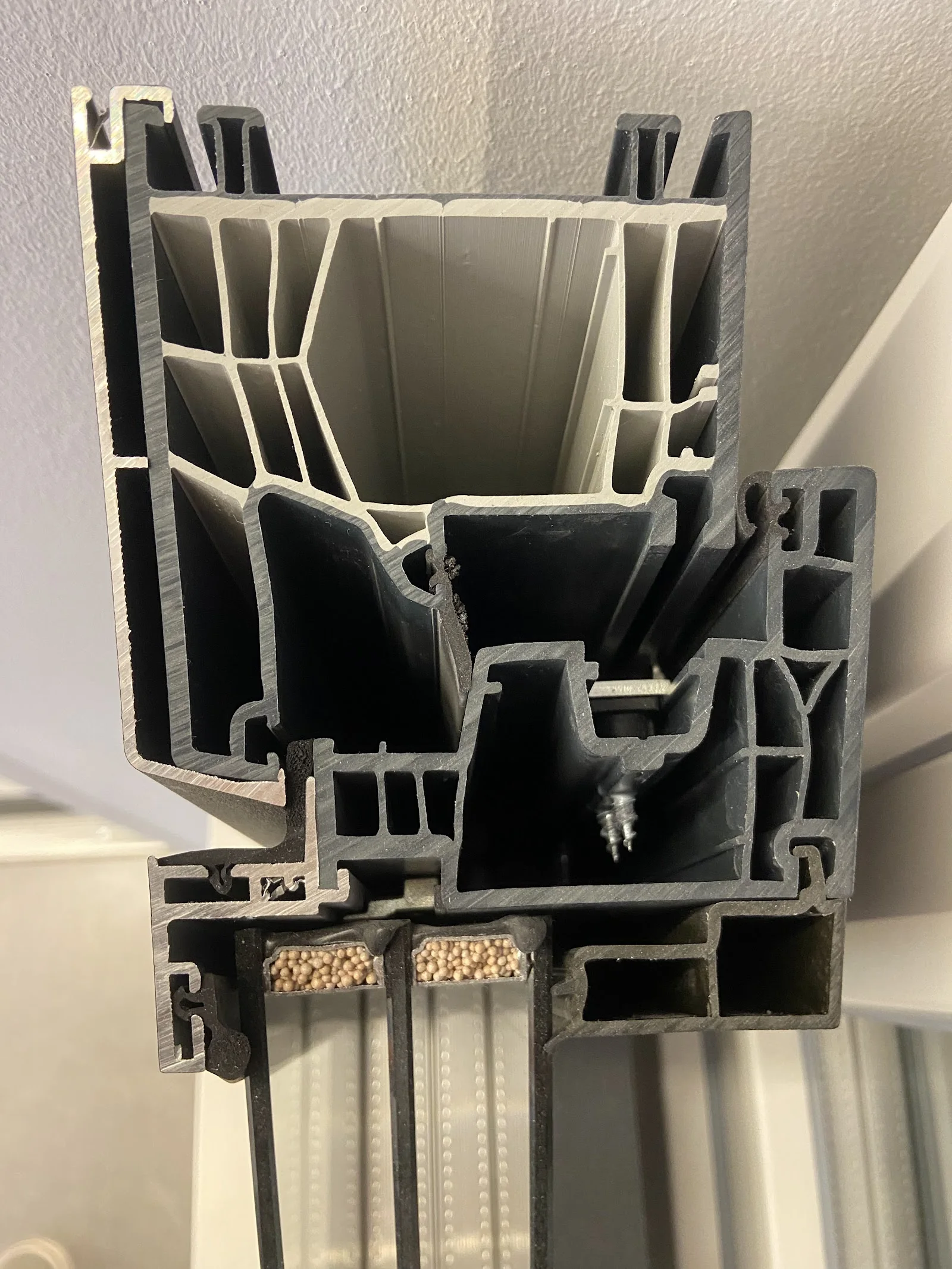 Sección real de un perfil de ventana de PVC antracita con sus cámaras y el doble acristalamiento